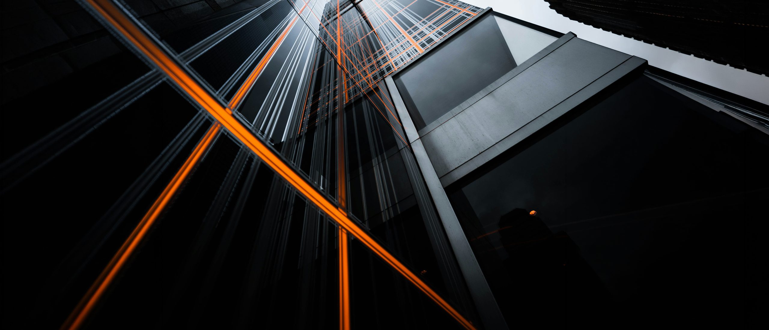 Looking up between glass towers, orange light streaks crossing the frame. Black at 55% over the whole image so white type holds. Desktop crop takes the lower-left third where the streaks converge; mobile keeps that convergence point in the upper half.