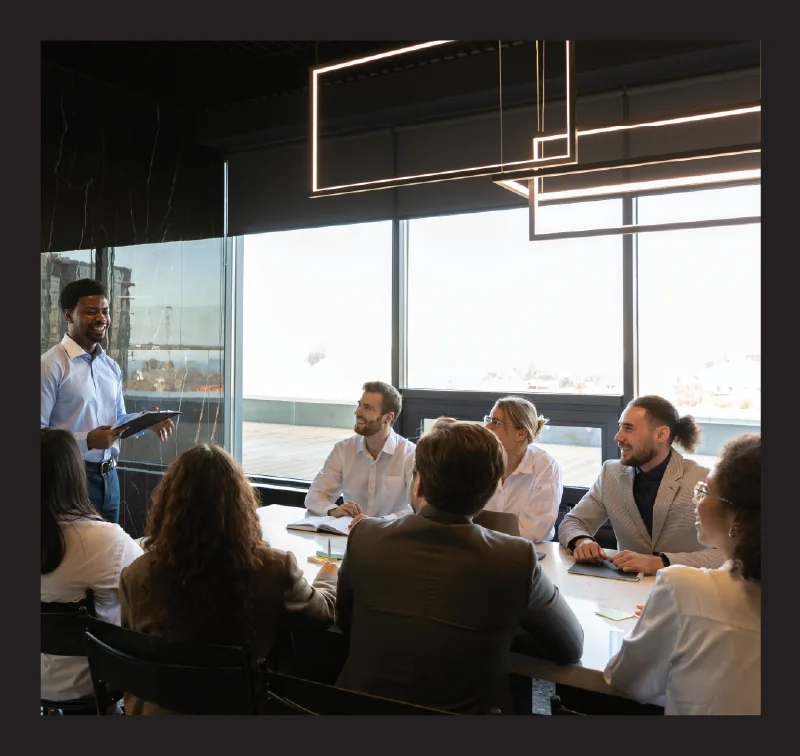Building Teams — one person presenting to a seated group. Midjourney, black frame baked in, shown whole and uncropped.